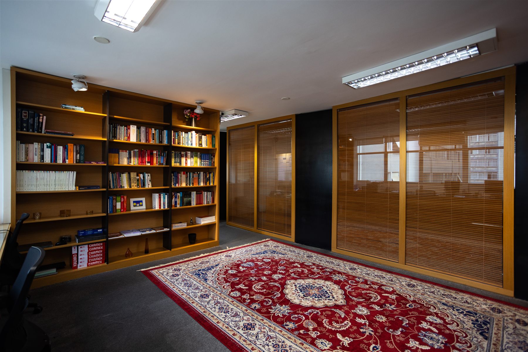 Biblioteca do escritório, com estantes de livros jurídicos e tapete vermelho